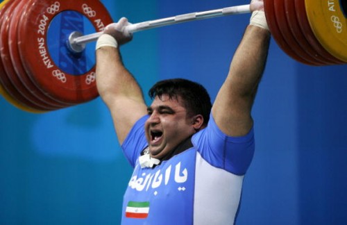 Athens, GREECE:  Hossein Rezazade of Iran lifts en route to a gold medal in the men's super heavyweight +105 kg Olympic weightlifting competition at Nikaia Olympic Weightlifting Hall in Athens 25 August 2004. Rezazadeh won the gold medal with a world-record-breaking display in the clean and jerk of 263.5 kg, beating his own previous record of 263 kg. AFP PHOTO / FAYEZ NURELDINE  (Photo credit should read FAYEZ NURELDINE/AFP/Getty Images)